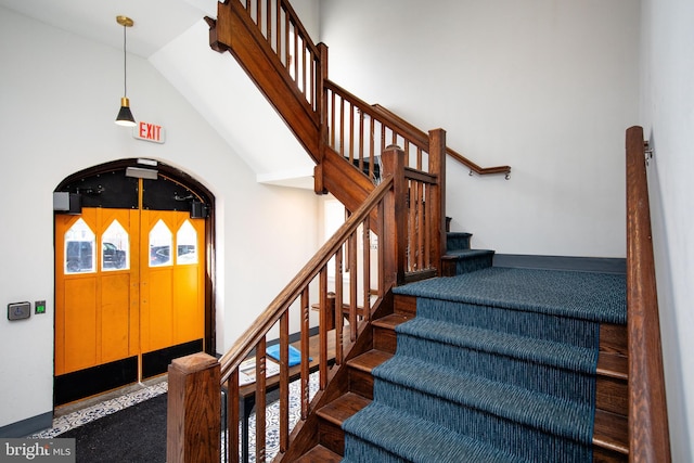 stairs with arched walkways, vaulted ceiling, and baseboards