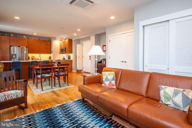 living room featuring light wood-type flooring, visible vents, and recessed lighting