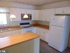 kitchen featuring butcher block countertops, white cabinets, a sink, and freestanding refrigerator