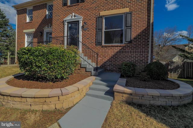 doorway to property with fence and brick siding