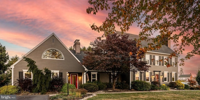 colonial-style house with a balcony, a chimney, and a shingled roof