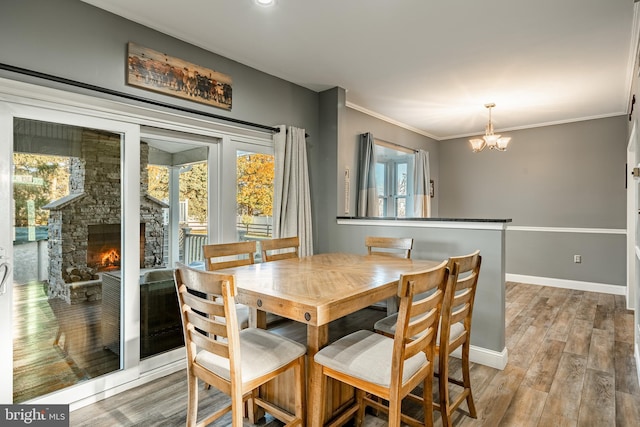 dining area with light wood-style flooring, a fireplace, crown molding, and baseboards