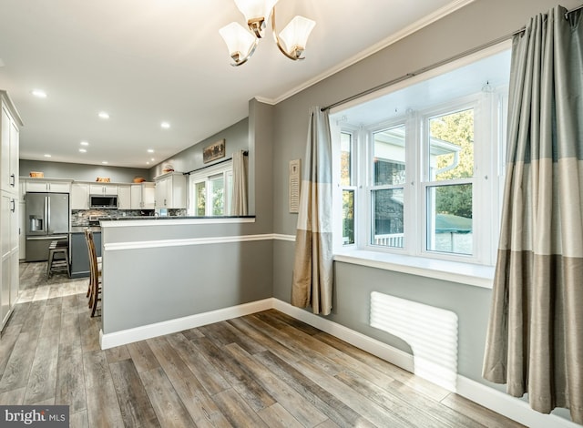 kitchen with baseboards, decorative backsplash, light wood-style floors, white cabinets, and stainless steel appliances