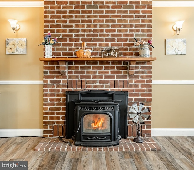 interior details featuring ornamental molding, a wood stove, baseboards, and wood finished floors