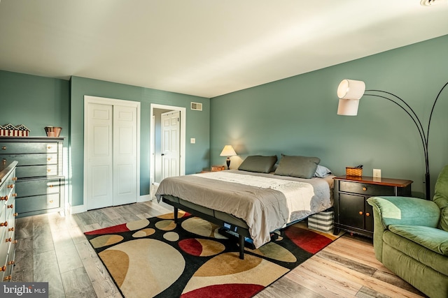 bedroom with visible vents, baseboards, a closet, and wood finished floors