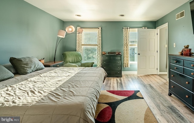 bedroom featuring visible vents, baseboards, and wood finished floors