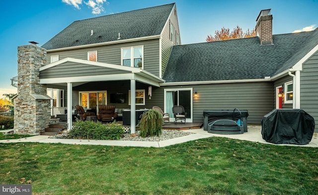 back of house with a lawn, an outdoor hangout area, a chimney, and roof with shingles