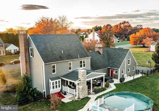 rear view of house with a yard, a chimney, a patio, and fence