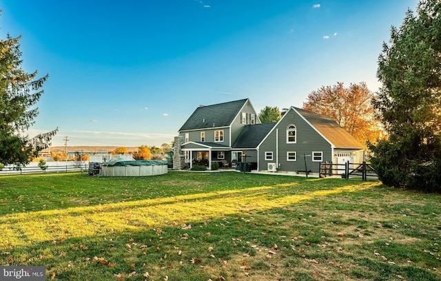 rear view of house featuring a fenced in pool, a patio, a yard, and fence