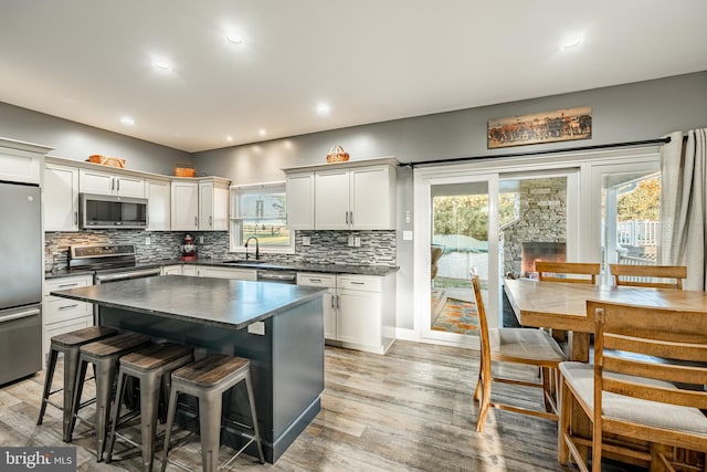 kitchen with a breakfast bar, a sink, dark countertops, stainless steel appliances, and light wood-style floors