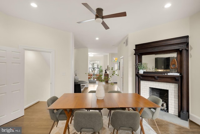 dining area featuring light wood-style flooring, recessed lighting, a fireplace, visible vents, and a ceiling fan