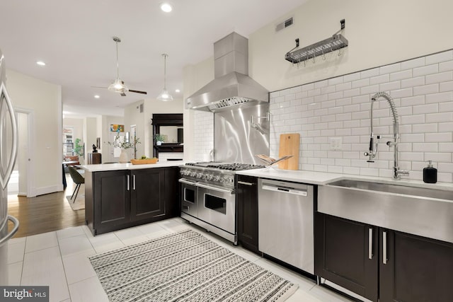 kitchen with island exhaust hood, light countertops, backsplash, appliances with stainless steel finishes, and a sink