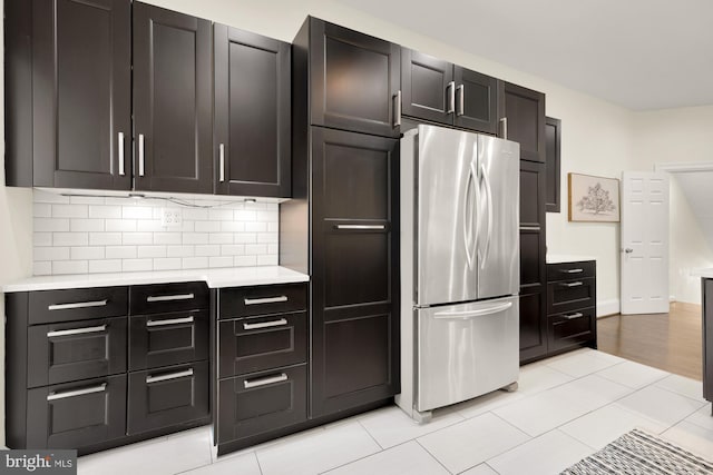 kitchen featuring light countertops, tasteful backsplash, light tile patterned flooring, and freestanding refrigerator