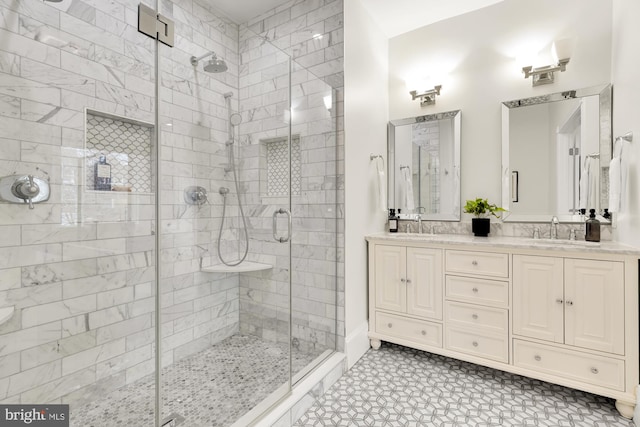 bathroom featuring double vanity, a stall shower, and a sink