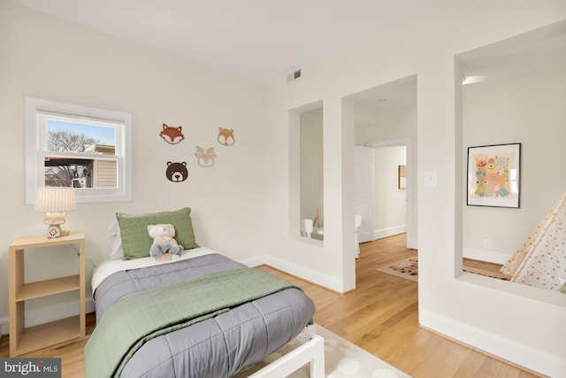 bedroom featuring visible vents, baseboards, and wood finished floors