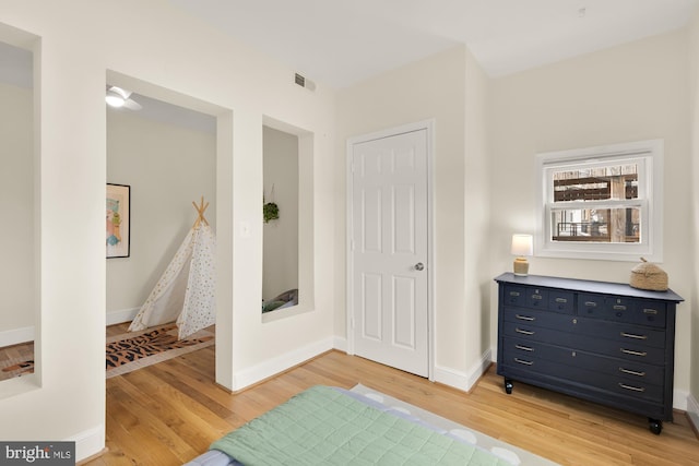 bedroom featuring light wood-style flooring, visible vents, and baseboards