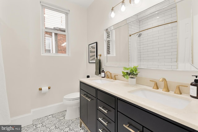 full bath featuring double vanity, baseboards, a sink, and tile patterned floors