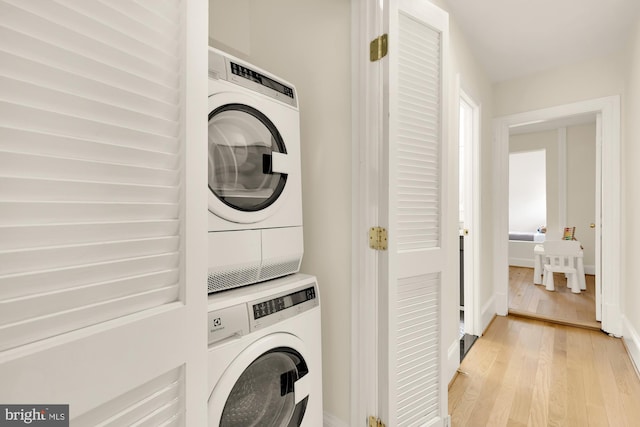 washroom featuring laundry area, light wood finished floors, and stacked washer and clothes dryer