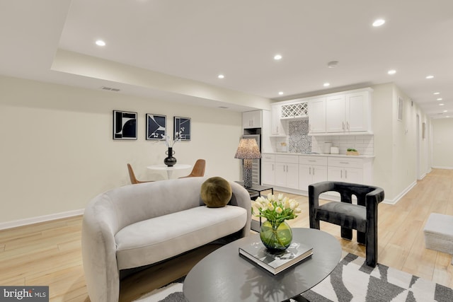 living area with light wood-style floors, baseboards, visible vents, and recessed lighting