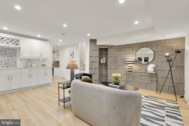 living area featuring a decorative wall, recessed lighting, and light wood-style floors