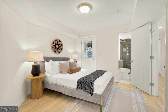 bedroom with light wood-type flooring, baseboards, and connected bathroom