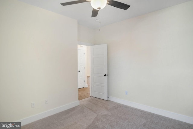 spare room featuring a ceiling fan, light carpet, and baseboards