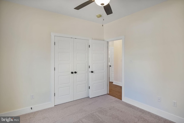 unfurnished bedroom featuring a ceiling fan, a closet, light colored carpet, and baseboards