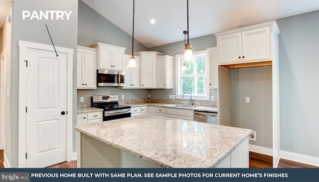 kitchen with stainless steel appliances, a center island, white cabinetry, hanging light fixtures, and light stone countertops