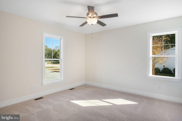 unfurnished room with baseboards, ceiling fan, visible vents, and light colored carpet