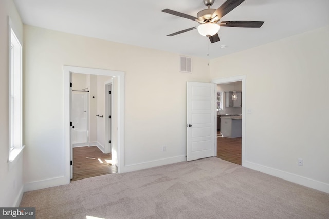 unfurnished bedroom featuring light colored carpet, visible vents, baseboards, and ensuite bathroom