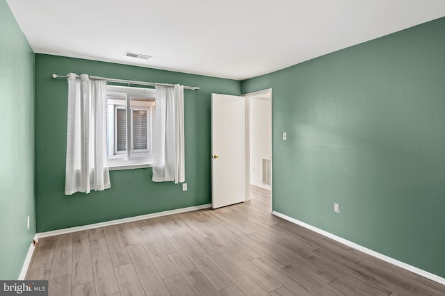 unfurnished room featuring visible vents, baseboards, and wood finished floors