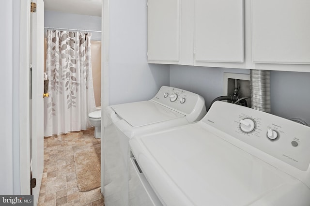 laundry room with stone finish flooring, cabinet space, and washing machine and clothes dryer