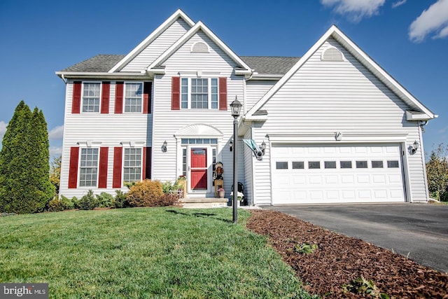 traditional-style home with driveway, entry steps, an attached garage, and a front yard