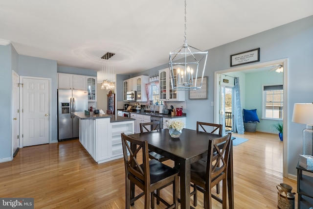 dining area with baseboards, light wood-type flooring, and a notable chandelier