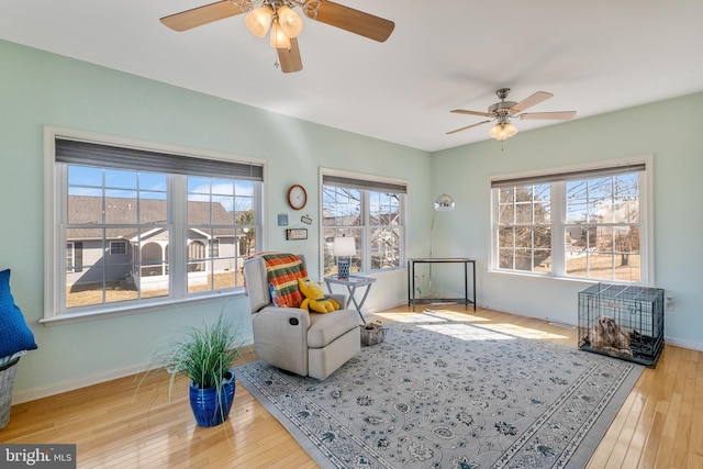 sitting room with ceiling fan, baseboards, and hardwood / wood-style flooring