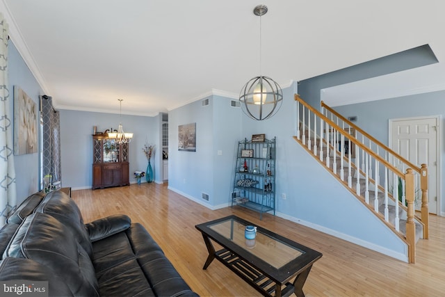 living area featuring a chandelier, wood finished floors, baseboards, and stairs