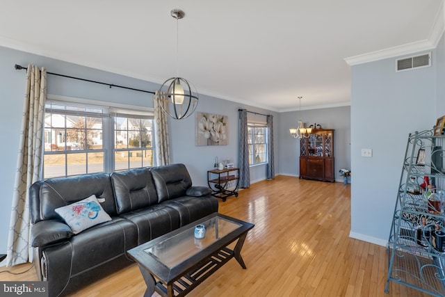 living area with a chandelier, visible vents, baseboards, ornamental molding, and light wood finished floors