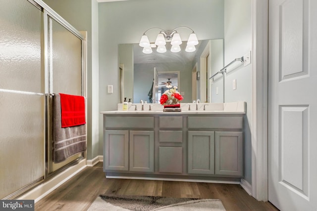 bathroom featuring double vanity, a shower stall, a sink, and wood finished floors