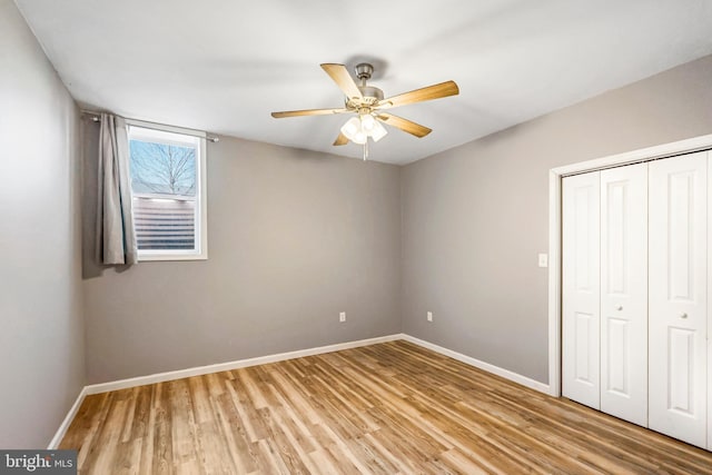 unfurnished bedroom with a closet, ceiling fan, light wood-style flooring, and baseboards