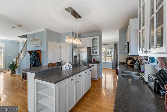 kitchen featuring stainless steel appliances, dark countertops, visible vents, and a sink