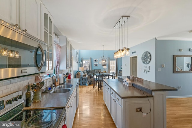 kitchen with stainless steel appliances, dark countertops, decorative backsplash, light wood-style floors, and a sink