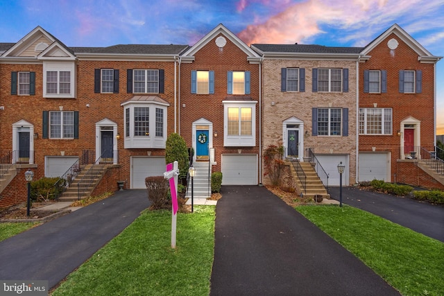 townhome / multi-family property featuring driveway, a garage, and brick siding