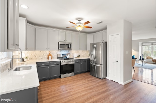 kitchen with gray cabinetry, a sink, visible vents, light wood-style floors, and appliances with stainless steel finishes