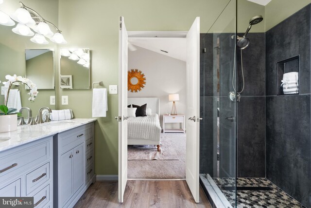 ensuite bathroom featuring wood finished floors, a tile shower, a sink, and ensuite bathroom