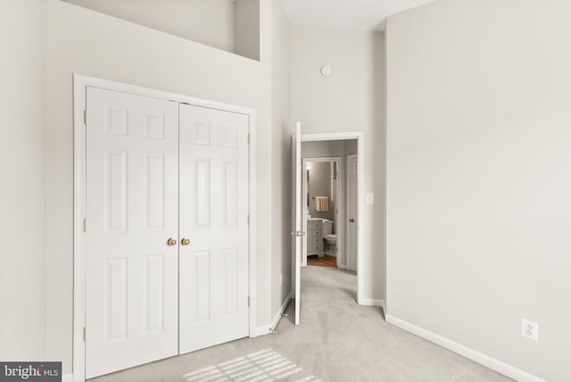 unfurnished bedroom with baseboards, a closet, and light colored carpet