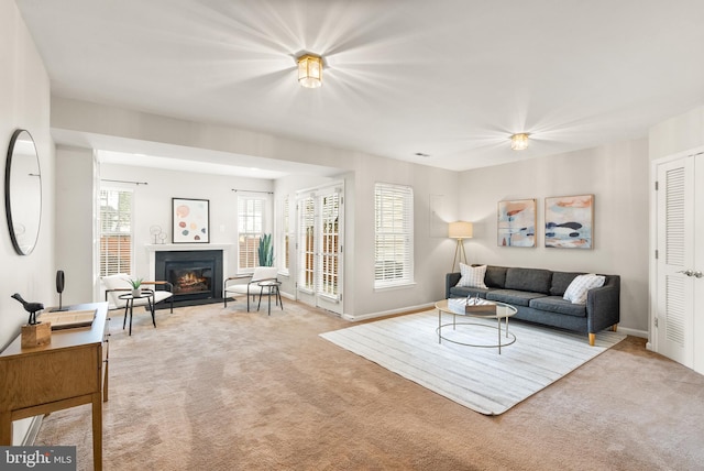 carpeted living area with a fireplace with flush hearth and baseboards