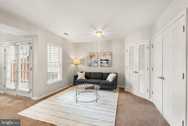 carpeted living area featuring visible vents and baseboards