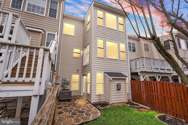 back of house at dusk with a patio area, fence, and central air condition unit