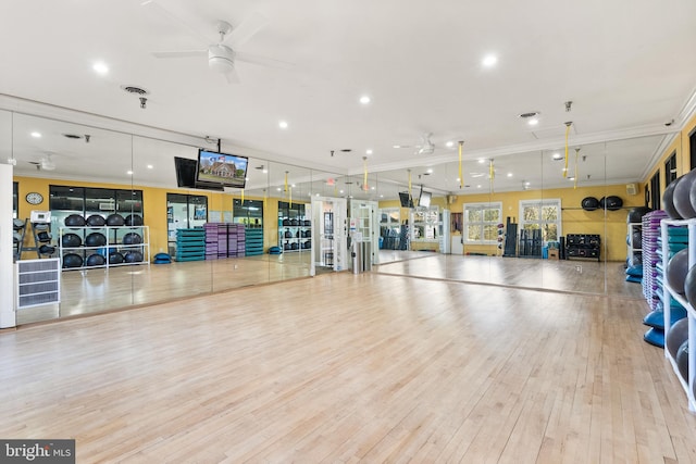 workout area with ceiling fan, visible vents, wood finished floors, and ornamental molding