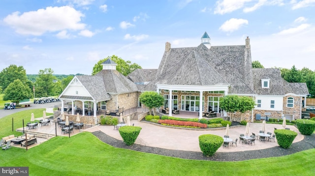 rear view of house featuring stone siding and a patio area